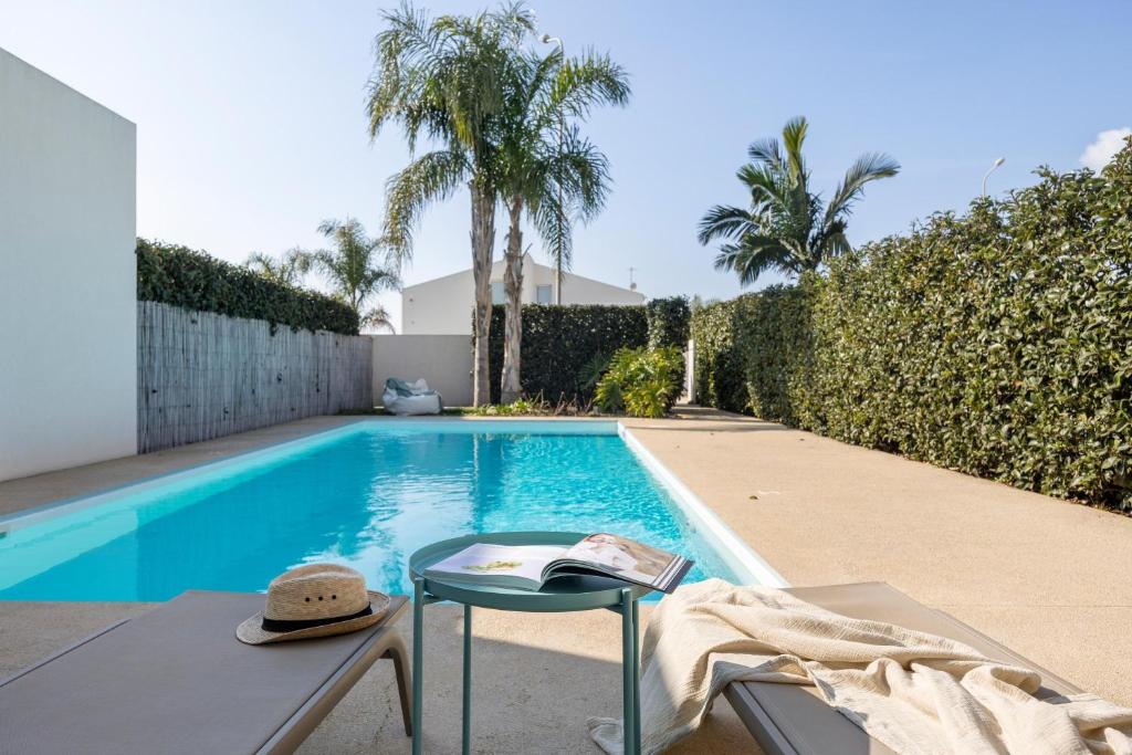 a swimming pool with a table and chairs next to a house at Villa D'Argento in Ragusa