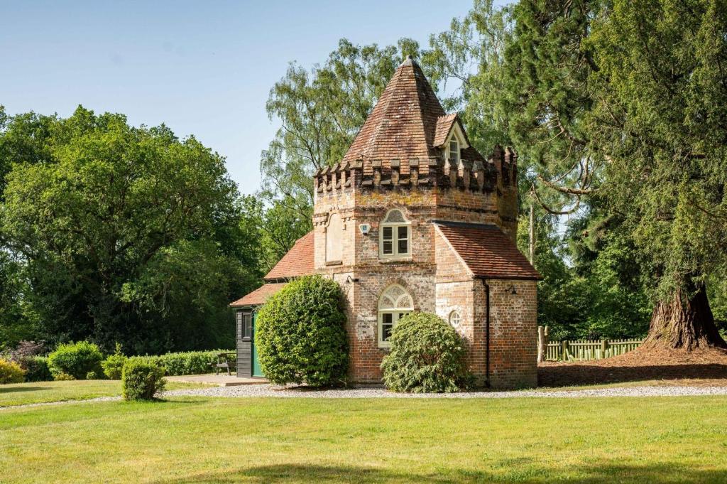 an old brick building with a tower in a field at Grimsbury Castle in Thatcham