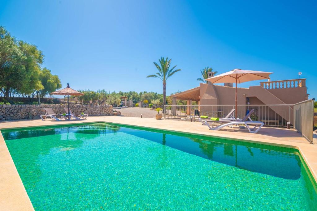 a swimming pool with blue water in front of a house at Son Morro in Santa Margalida