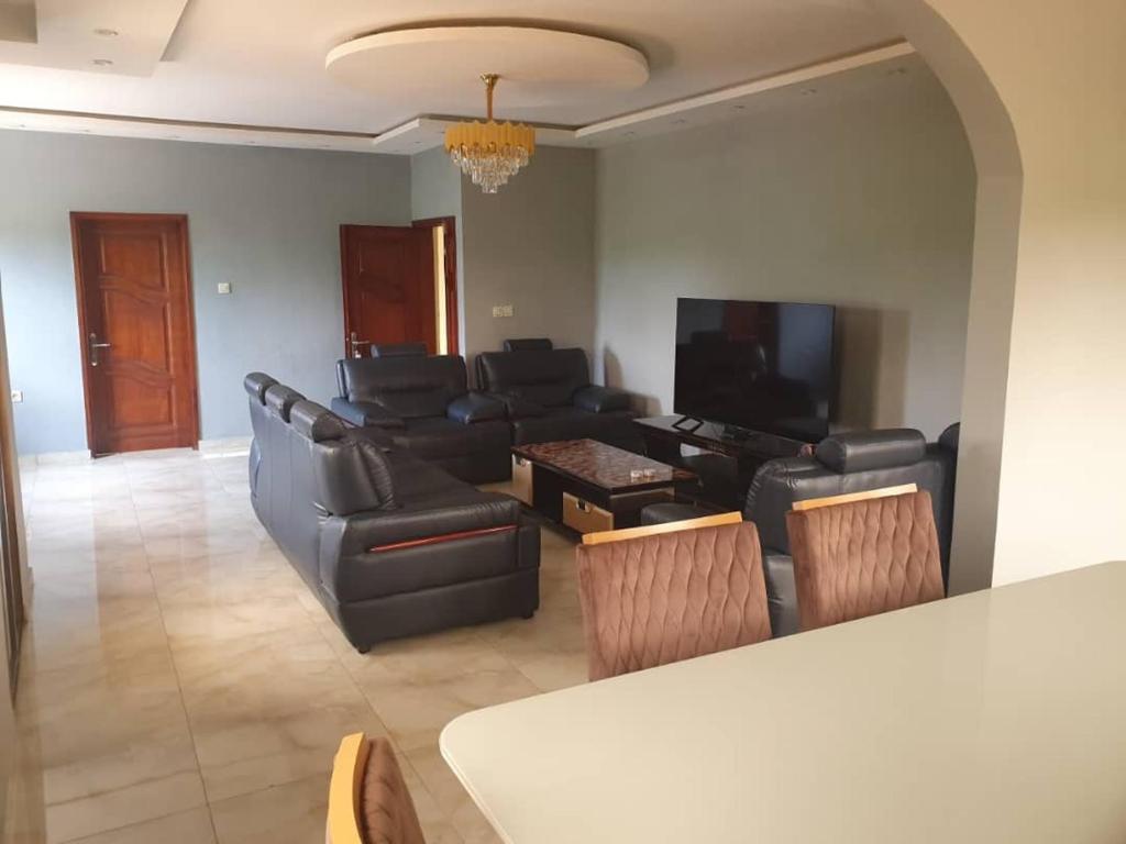 a living room with black leather furniture and a flat screen tv at villa HALAL in Mfou