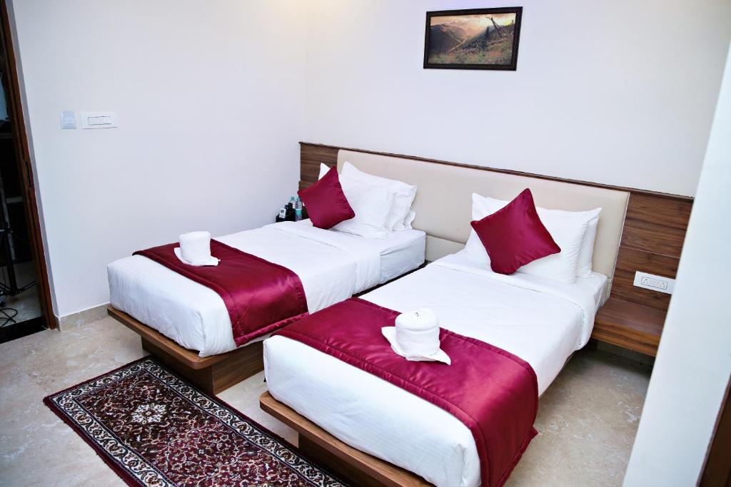 two beds in a hotel room with red and white pillows at Hotel Grand Villa in Yelahanka