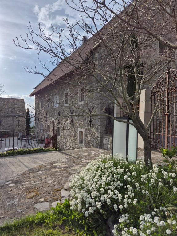 a stone building with white flowers in front of it at Saunu dvor - Saunus court in Tolminski Lom
