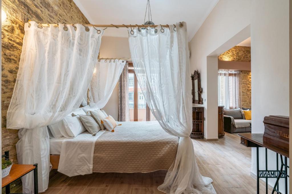 a bedroom with a canopy bed with white curtains at Absinthia Legacy in Soroni