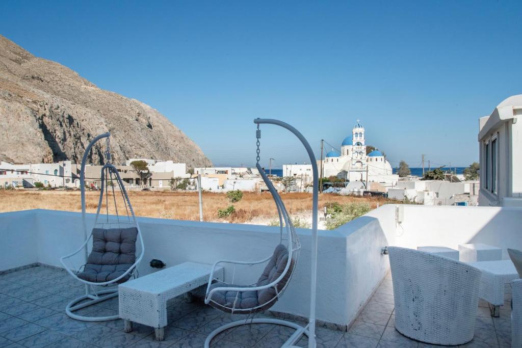 two chairs and a bench on a balcony with a view at Pleasure Blackbeach Studios in Perissa