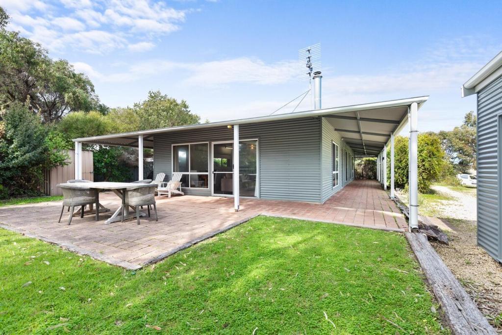 a patio with a table and chairs and a house at Fennell House in Robe