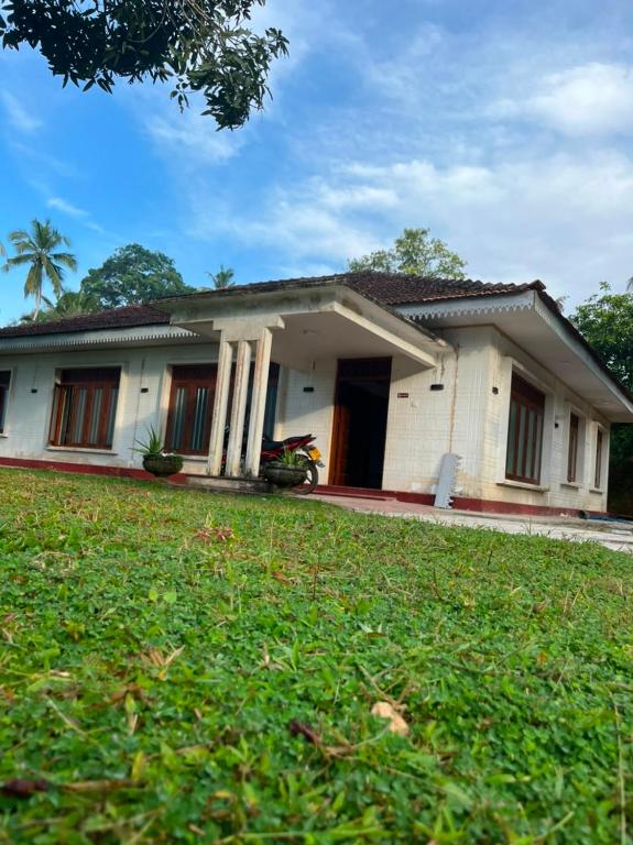 a white house with a lawn in front of it at The Highland Manor in Weligama
