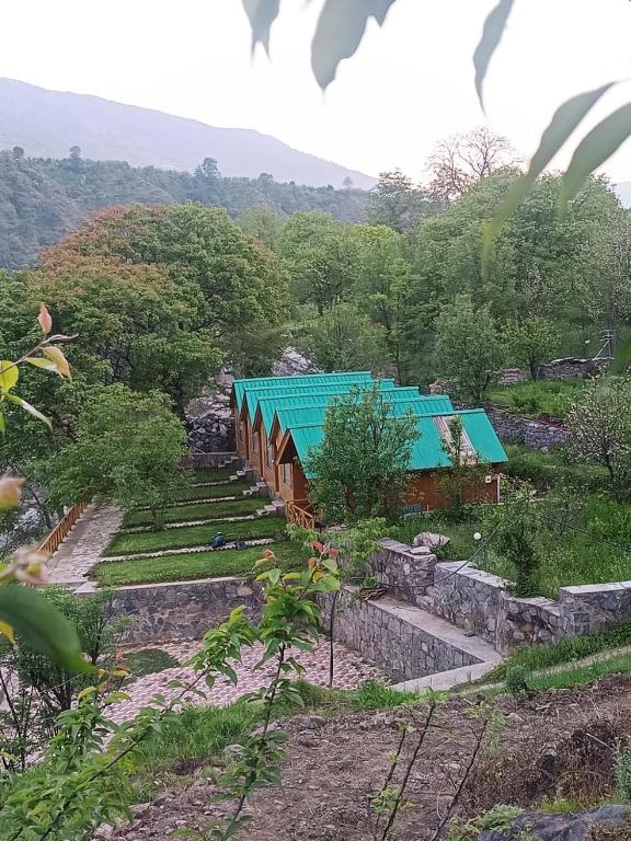 a building with a blue roof in a field at Wildwood Cabins Manali in Kulu
