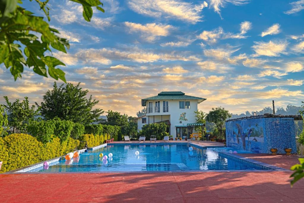 a swimming pool with a building in the background at Corbett Treat Resort in Rāmnagar