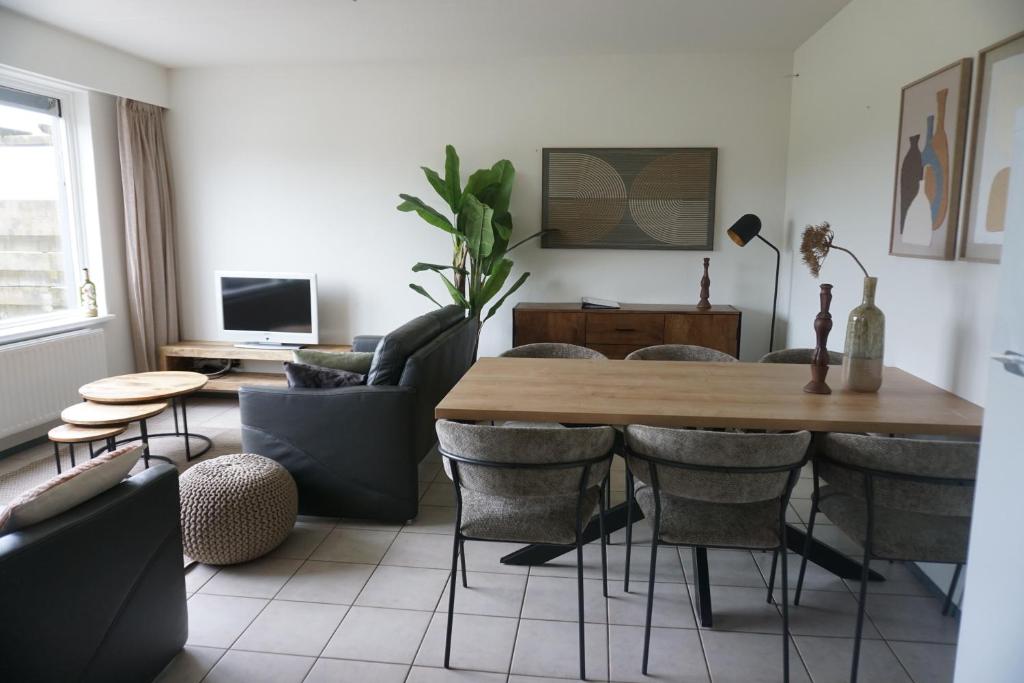 a living room with a wooden table and chairs at Kustverhuur, Oude manege Nieuwvliet, Nieuwvliet 1 - 2 in Nieuwvliet