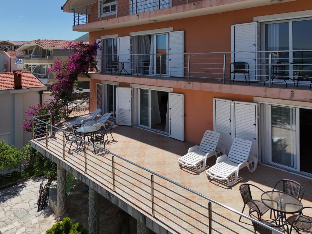 a balcony with chairs and tables on a building at Apartment Orange Blossom First Line & Pool 1 in Bijela