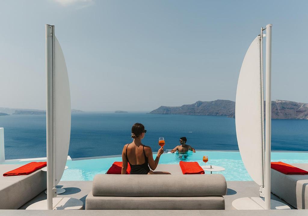 two people sitting in a pool with glasses of wine at Saint Santorini in Oia
