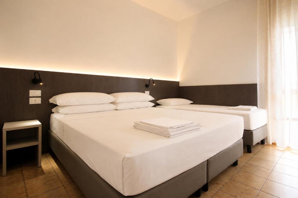 two beds in a room with white sheets and pillows at Residence Columbia in Bibione