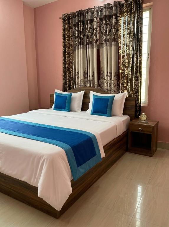 a bedroom with a large bed with blue pillows at Tapasya Palace in Gorakhpur