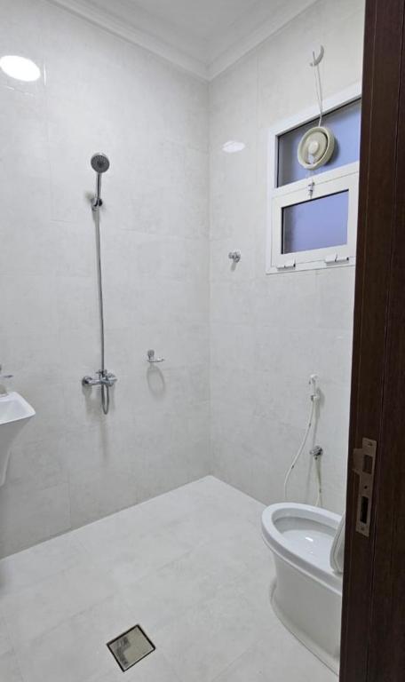 a white bathroom with a toilet and a window at Sahalnoot flats in Salalah