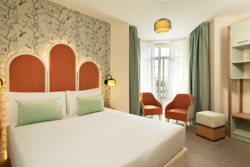 a bedroom with a large white bed and chairs at Hotel La Tonkine ex Olympia in Beausoleil