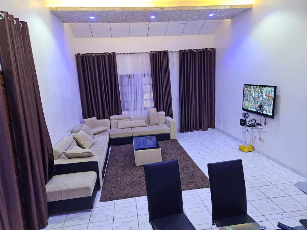 a living room with a couch and chairs and a tv at Le Rêve d'Or in Lomé