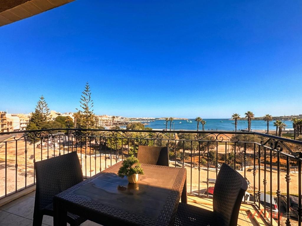 a table and chairs on a balcony with a view of the ocean at Elegant Seafront Duplex with Stunning Panoramic Views in Birżebbuġa