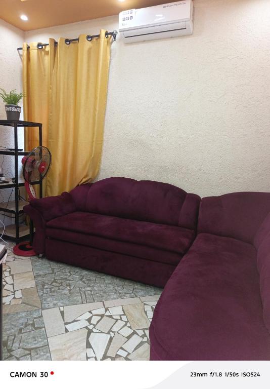 a living room with a purple couch in front of a window at or bleu in Lomé