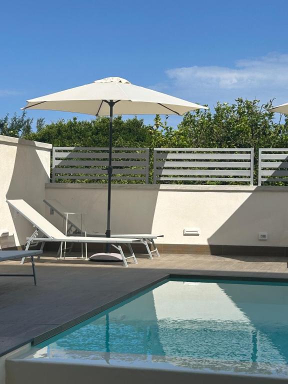 a swimming pool with an umbrella and chairs and a table and a pool at La BriSa in Capo dʼOrlando