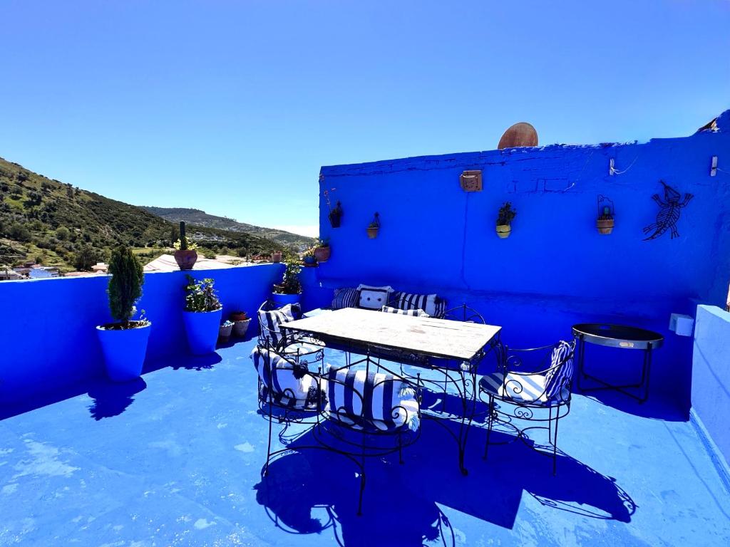 a blue building with a table and chairs on a patio at Casa Raselma - Rela Mountains & Spectacular Views in Chefchaouen