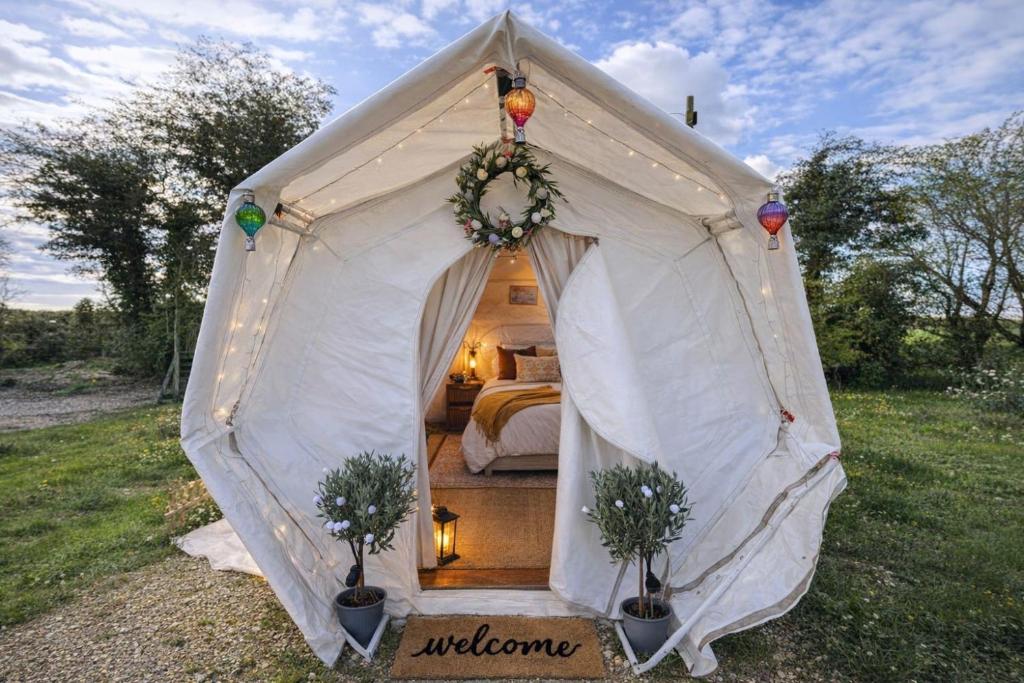 a white tent with a bed in a field at Pewsey Countryside Dome - Dog Friendly - Fire pit in Pewsey