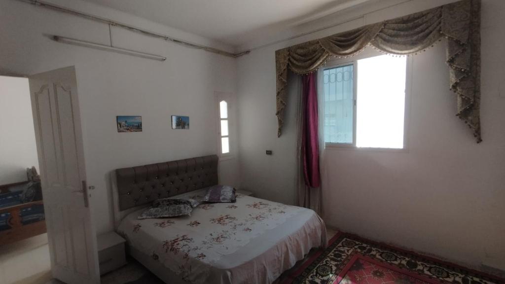 a small bedroom with a bed and a window at Maison Lyne in Hammamet