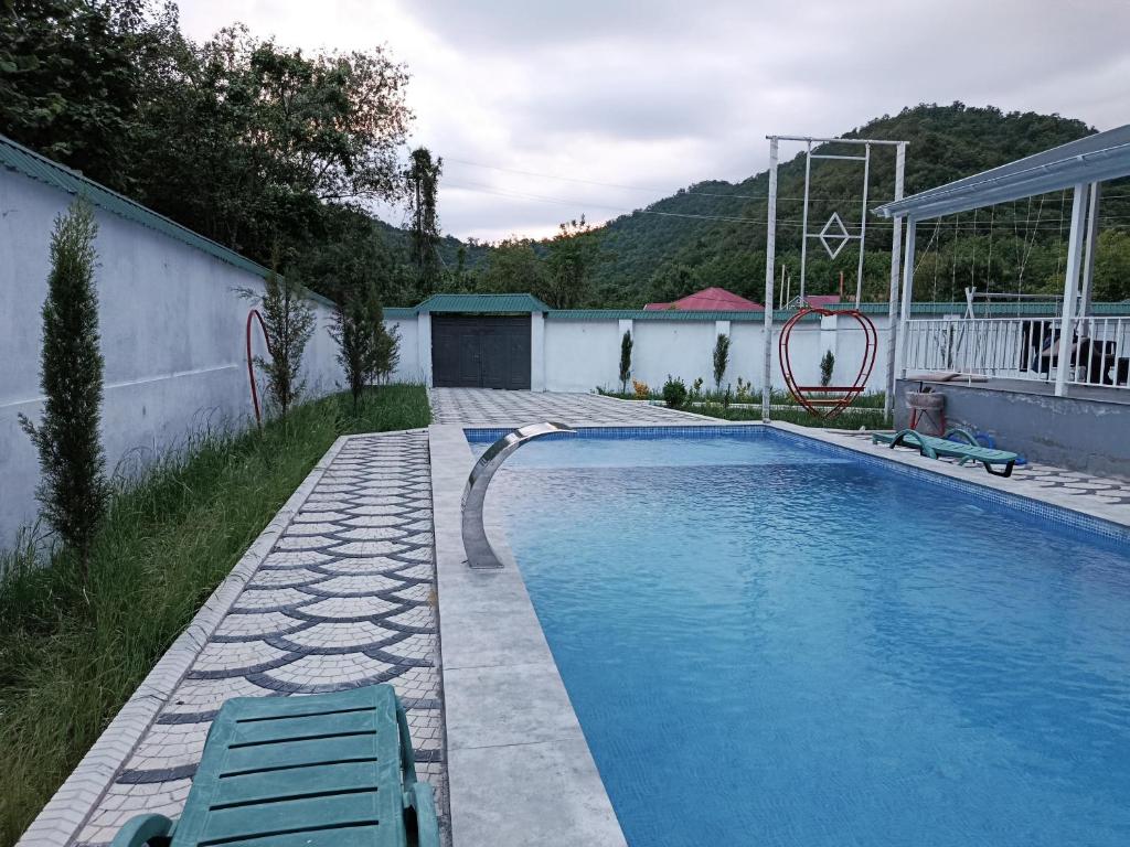 a swimming pool with two chairs in a backyard at White Gray House Gabala Vandam in Gabala
