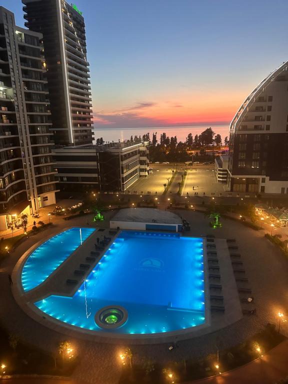 a large swimming pool in a city at night at Prestigio Sea view apart in Batumi