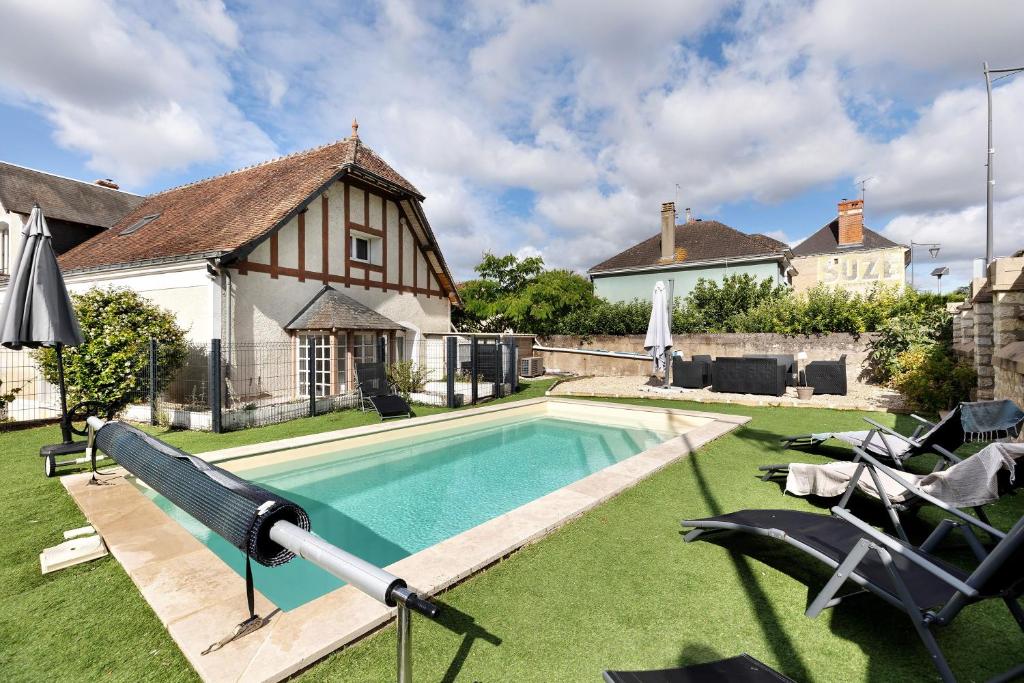 a swimming pool in the yard of a house at Gîte Le Rabelais in Thésée