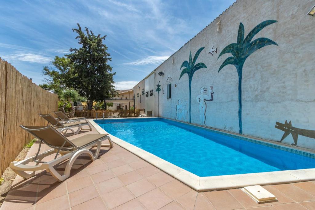a swimming pool with two chairs and a wall with a mural at Casa Rural Cal Pallol in Camarasa