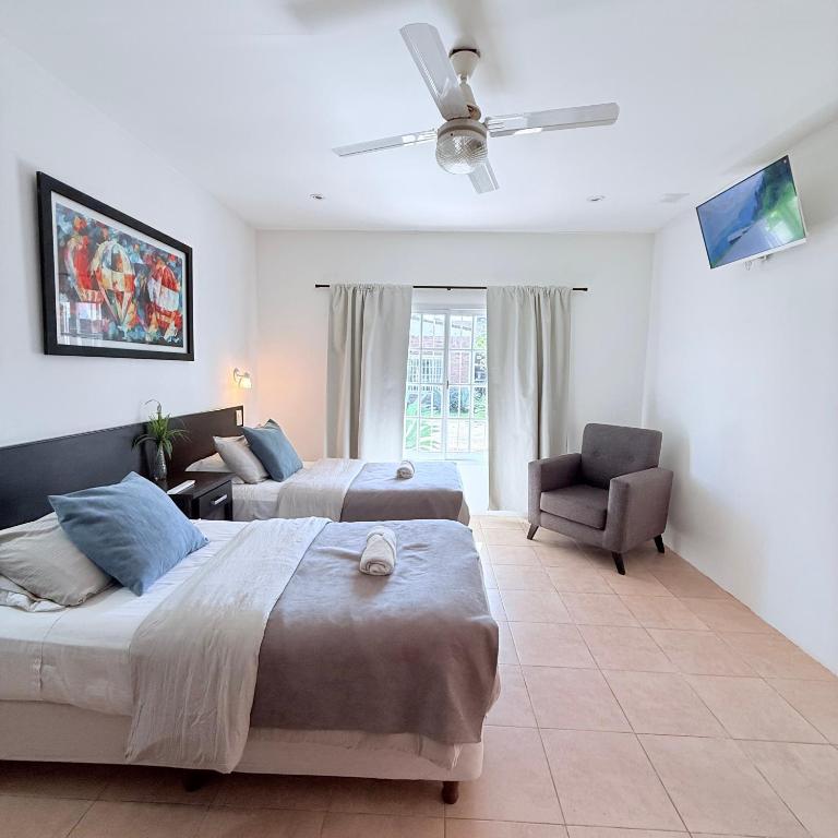 a bedroom with two beds and a chair and a ceiling fan at G8 Hermoso Monoambiente con Cochera 2 huéspedes in Villa Ángela