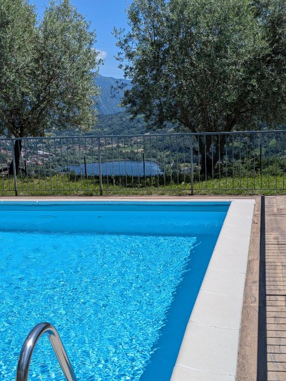 a blue swimming pool with trees in the background at La Magia del Lago in Ranzanico