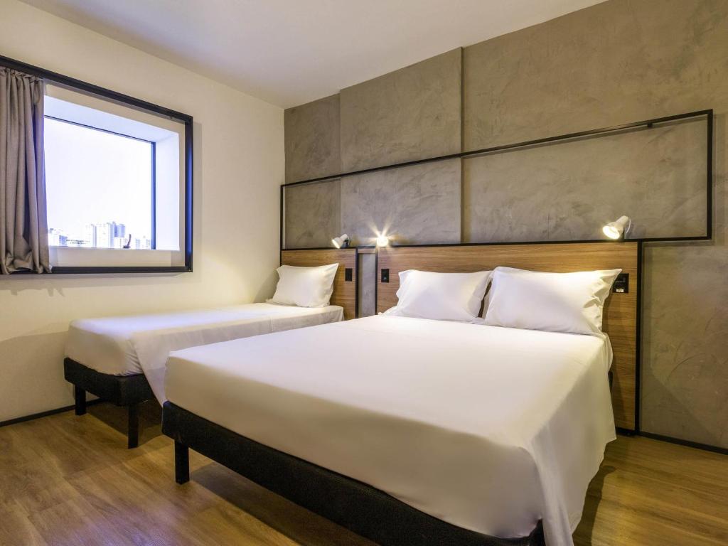 a hotel room with two beds and a window at ibis Ribeirao Preto Vila do Golf Shopping in Ribeirão Preto