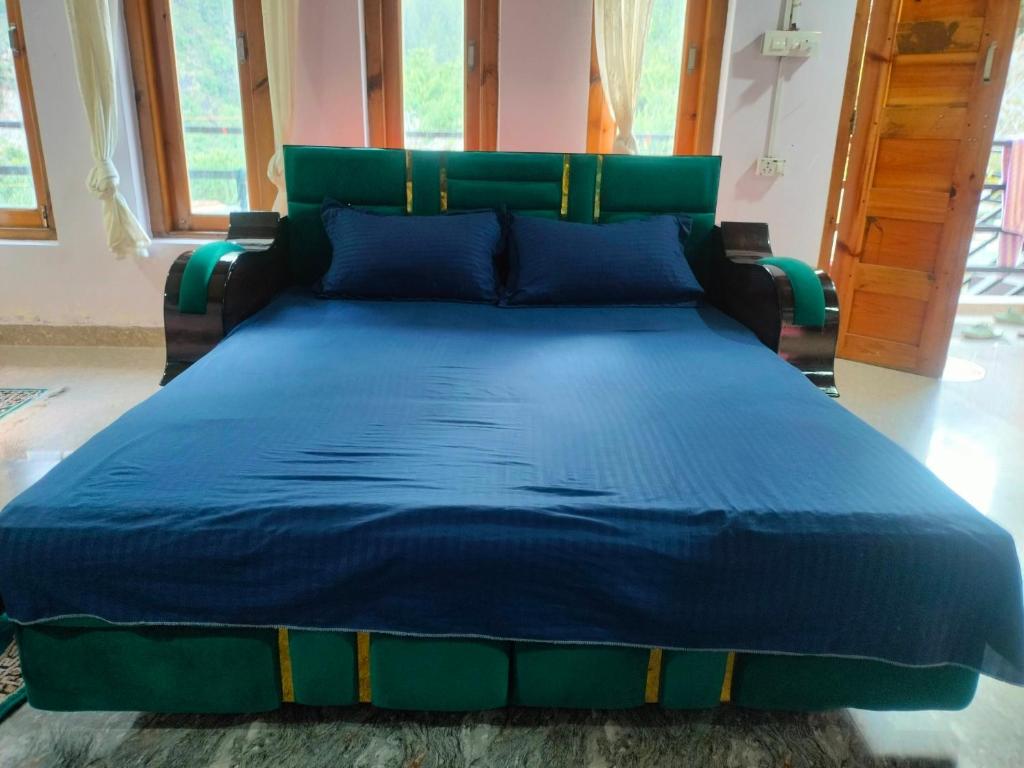 a bed in a room with a blue comforter at Routelahomestay in Gangnāni
