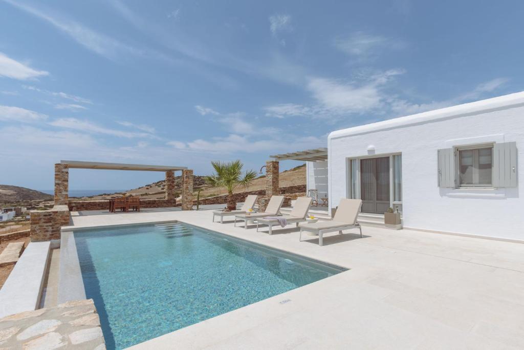 a villa with a swimming pool and lounge chairs at Bonatsa House in Agios Georgios