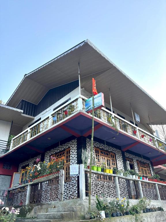 a building with a balcony with plants on it at Bikash Homestay in Mangpu