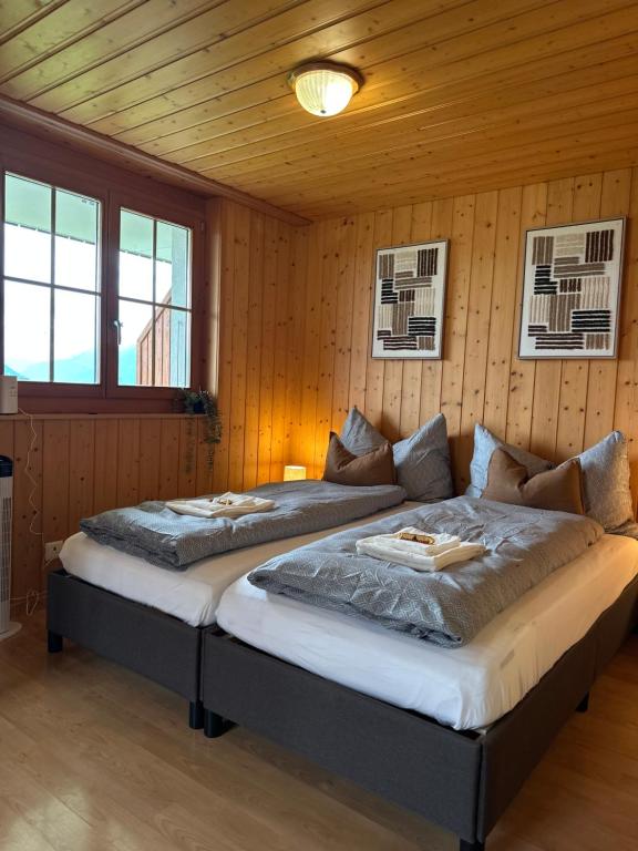 two beds in a room with wooden walls at CapoBnB, Montainview, Terrace in Aeschi bei Spiez