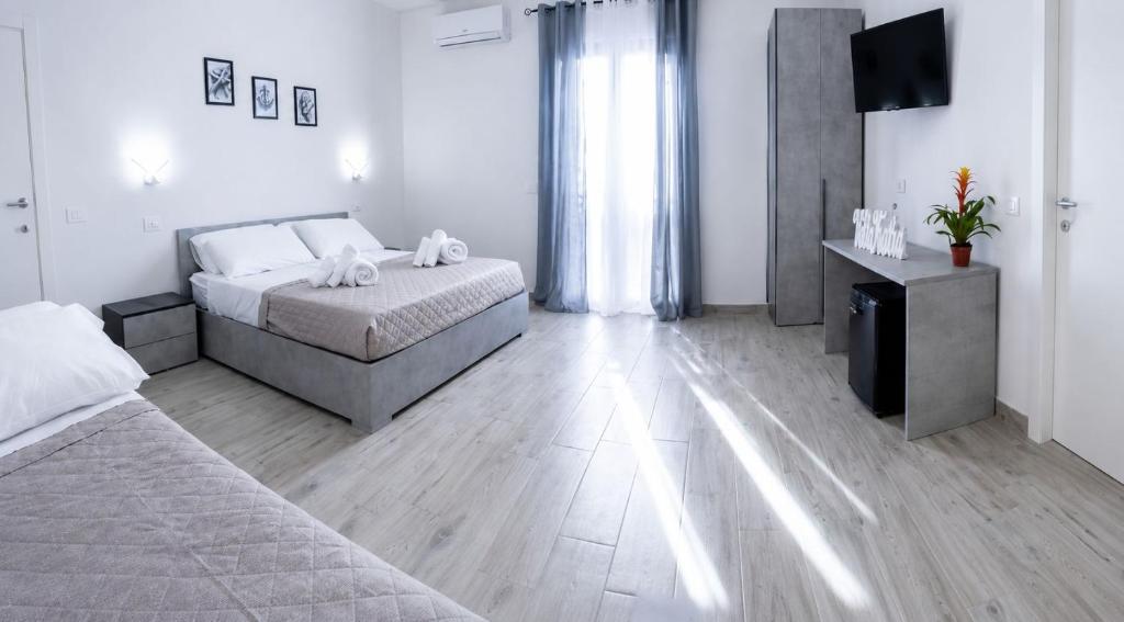 a bedroom with two beds and a flat screen tv at Villa Katia - Affittacamere in Torre Marino