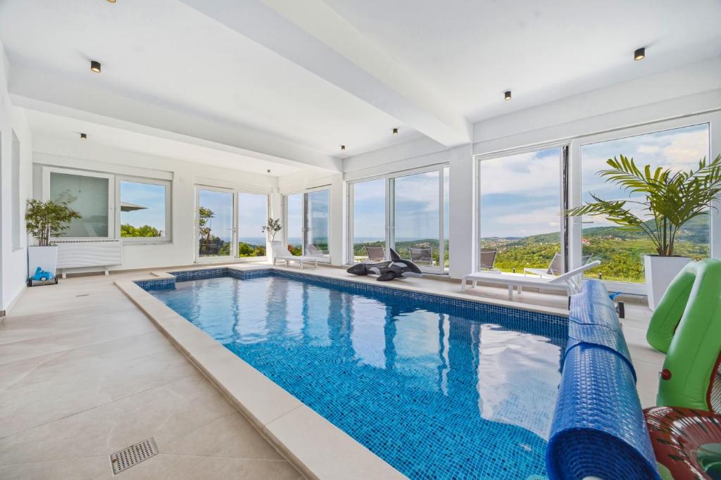 a large swimming pool in a living room with windows at Luxury Villa with Indoor Pool and Sauna in Zagreb