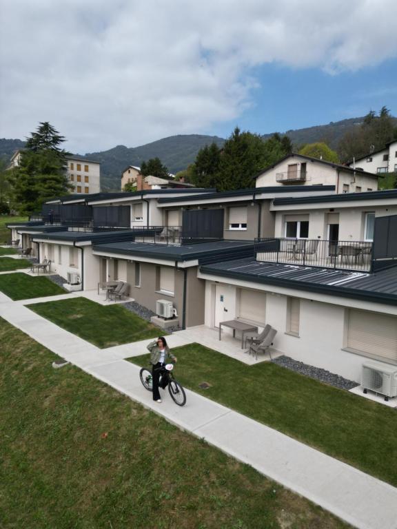 a person riding a bike on a sidewalk in front of buildings at BedE-Bike Apartments in Casazza