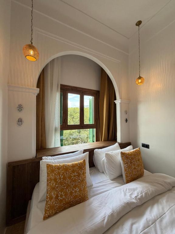a bedroom with a large white bed with a window at Riad los simbolos in Tétouan