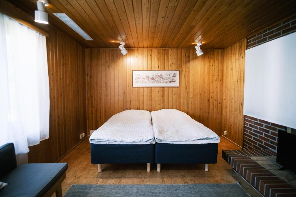 a bed in a room with a wooden wall at Näsby apartment with sauna in Houtskari
