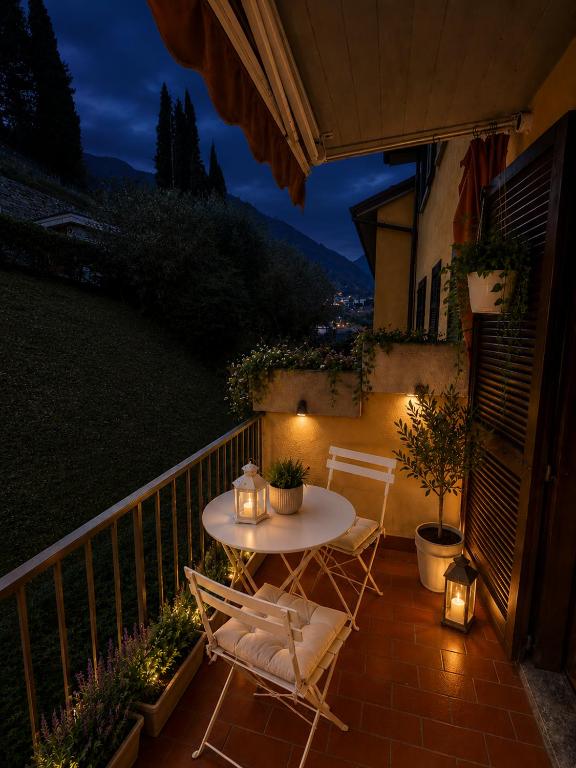 a table and chairs on a balcony at night at Frenk house over Varenna in Perledo