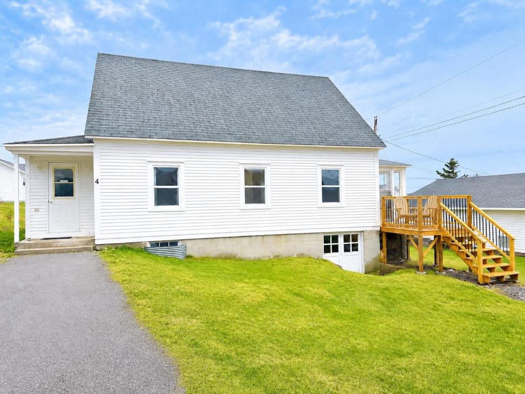 a white house with a porch and a deck at Gus & Nellie's Place in Twillingate