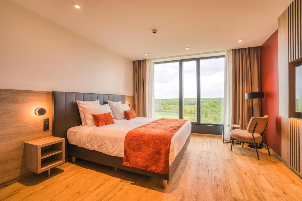 a hotel room with a bed and a large window at Bois d'Arlon Hotel & SPA in Arlon