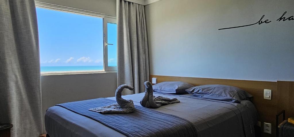 a bedroom with two swans on a bed with a window at Flat vista Mar -conforto e estilo em Ponta Negra-Natal in Natal