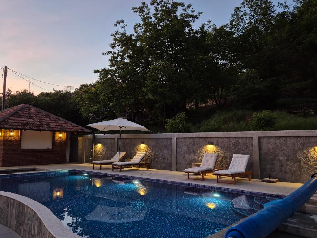ein Swimmingpool mit Liegestühlen und einem Sonnenschirm in der Unterkunft Serbina in Kandalica
