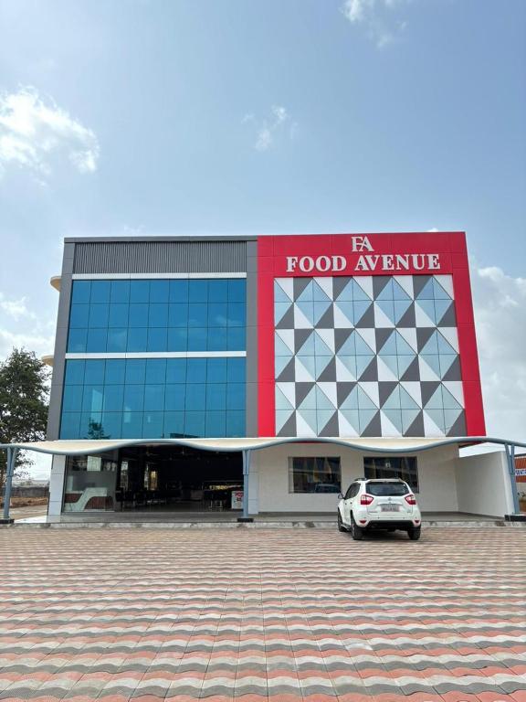 a building with a car parked in front of it at Hotel Food Avenue in Jāmb
