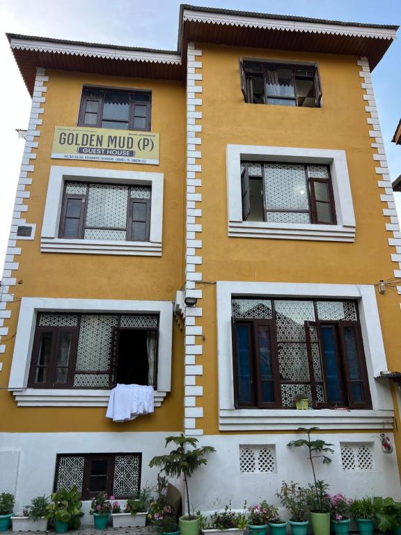 a yellow building with a laundry hanging out the window at Golden Mud in Srinagar