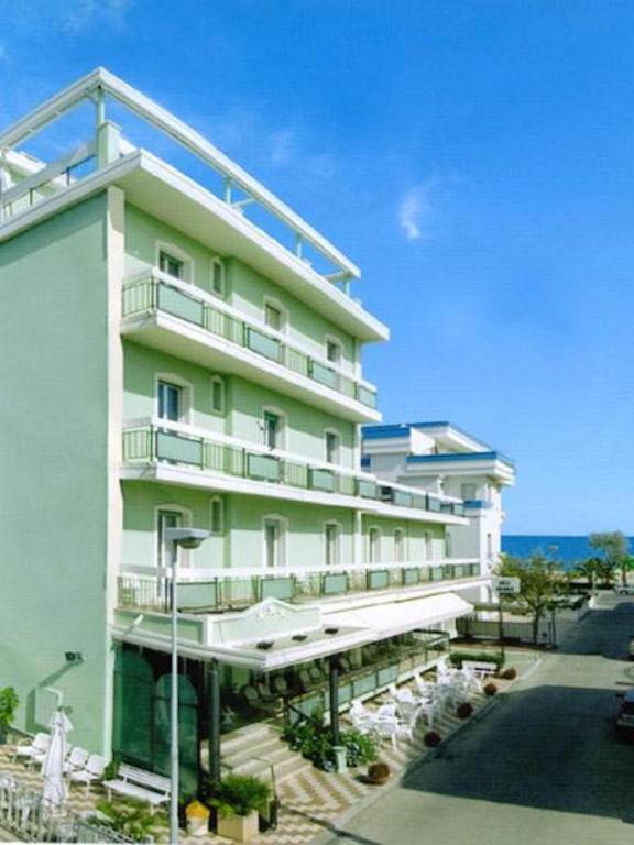 a large white building with tables and chairs at Hotel Dolores in Rimini